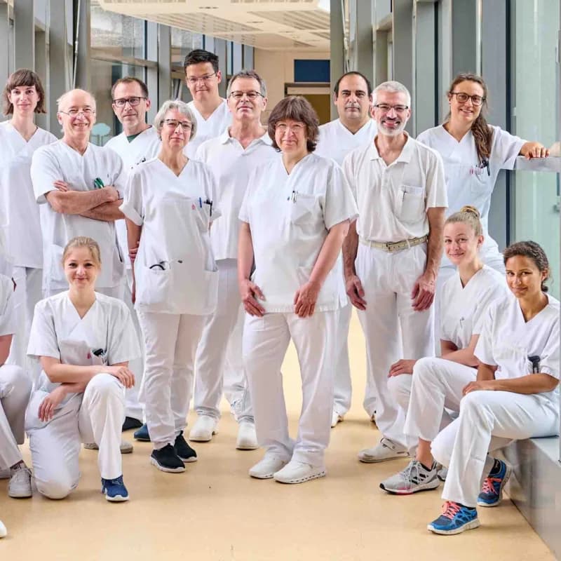Das medizinische Team der Chirurgie steht zusammen in einem Krankenhausflur und lächelt in die Kamera.