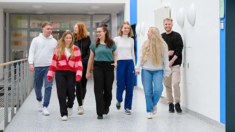 Auszubildene laufen in einer Gruppe einen Flur im SKK Bildungszentrum entlang und unterhalten sich untereinander.