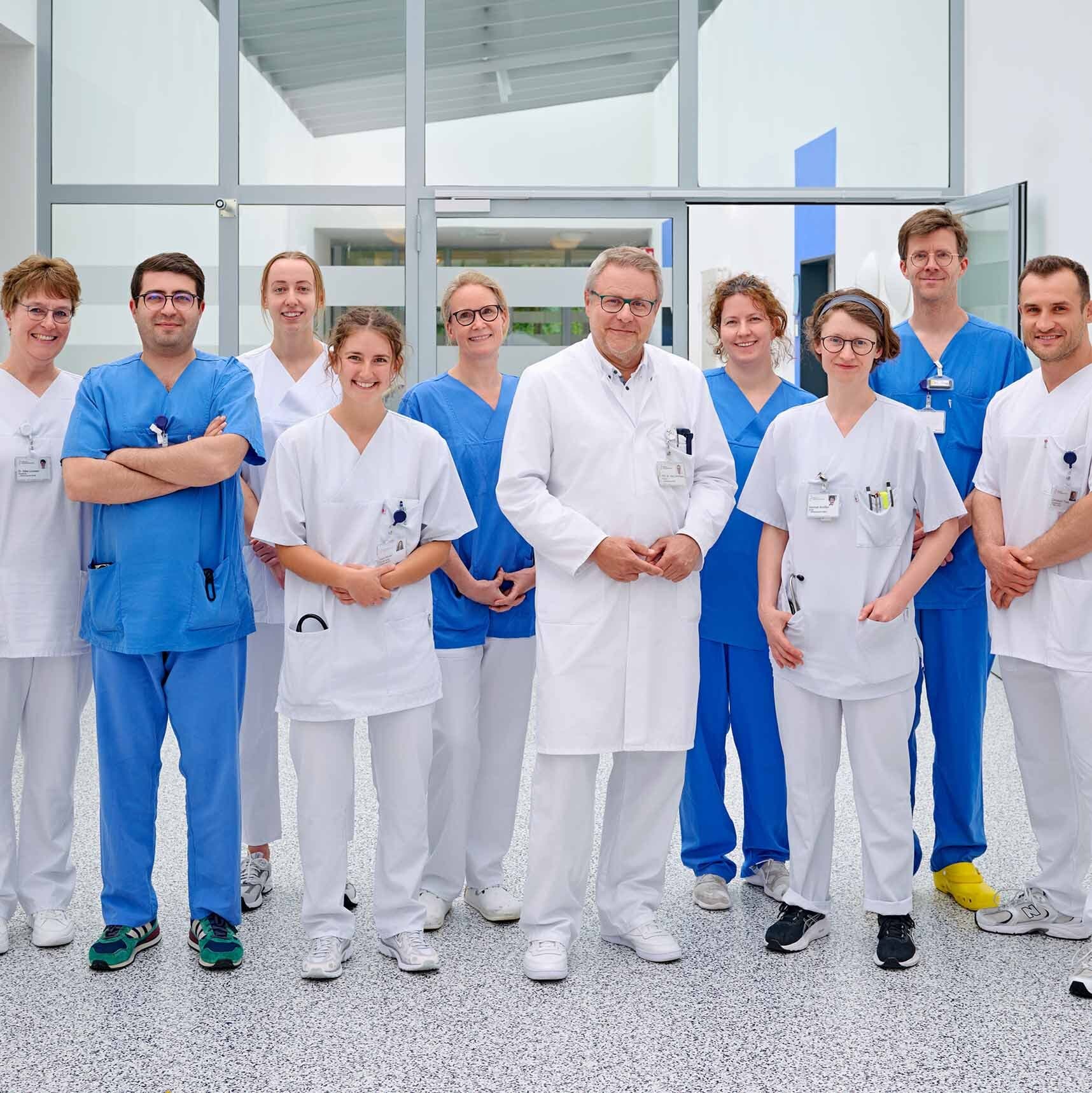 Mehrere medizinische Kolleginnen und Kollegen der ersten medzinischen Klinik stehen in einem Flur und lächeln in die Kamera.