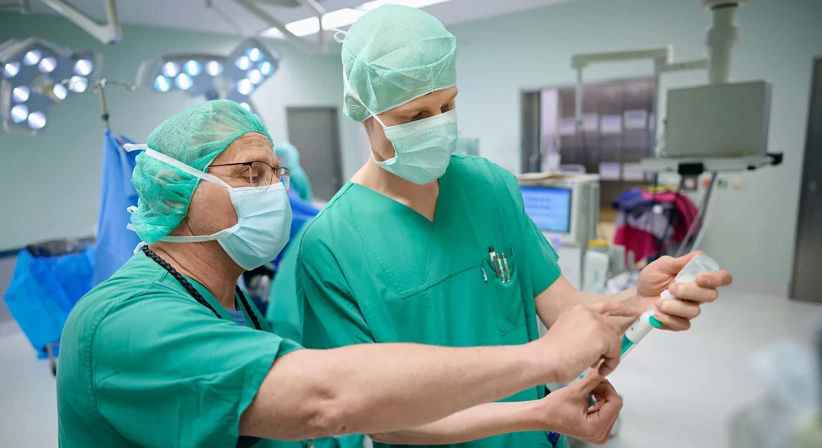 Zwei Anästhesietechnische Assistenten stehen im OP und bereiten die Narkose für eine anstehende Operation vor.